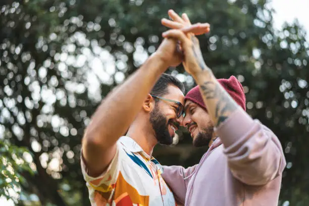 Photo of Gay couple touching hands in the public park