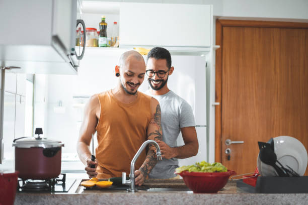 coppia lgbt che prepara cibo a casa - alternative health care foto e immagini stock