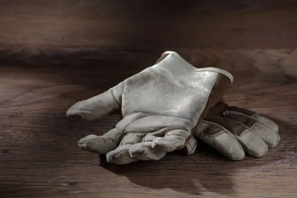 A pair of work gloves on a wood surface with window light