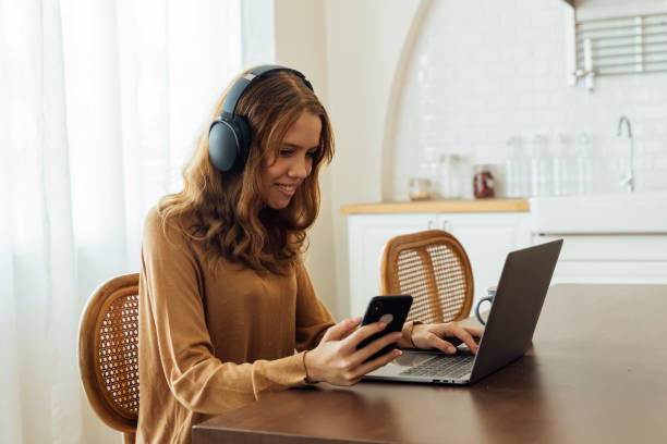 istock Girl using smartphone and laptop with headphones 1318372818