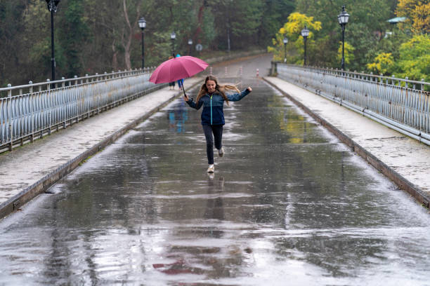istock Woman with umbrella having fun in rainy day 1318373803