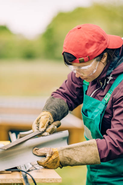 istock woman using file rasp for gripped sheet metal 1318377358