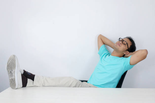 Calm smiling Young Asian Man relaxing at comfortable office chair hands behind head, happy man resting in office satisfied after work done, enjoying break with eyes closed, peace of mind, no stress tranquilo sonriente joven asiático se relaja en cómoda silla de oficina manos detrás de la cabeza, hombre feliz descansando en el cargo satisfecho después del trabajo hecho, disfrutando de descanso con los ojos cerrados, tranquilidad, sin estrés