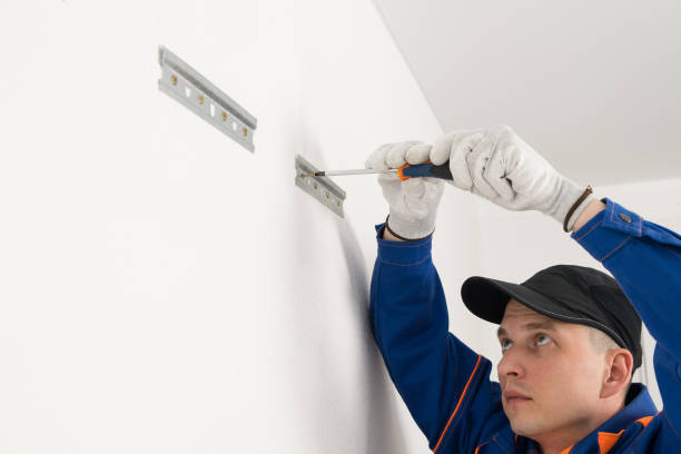 istock a worker screws fasteners to a white wall with self-tapping screws for hanging kitchen cabinets, using a screwdriver, bottom view 1318389287