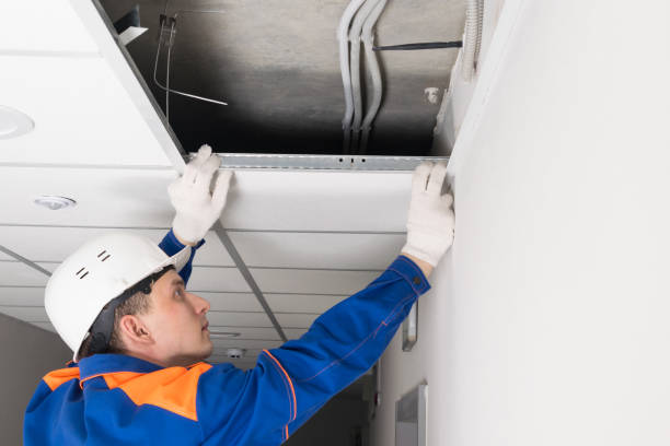 istock a worker in a helmet finishes the installation of a false ceiling, side view 1318389387