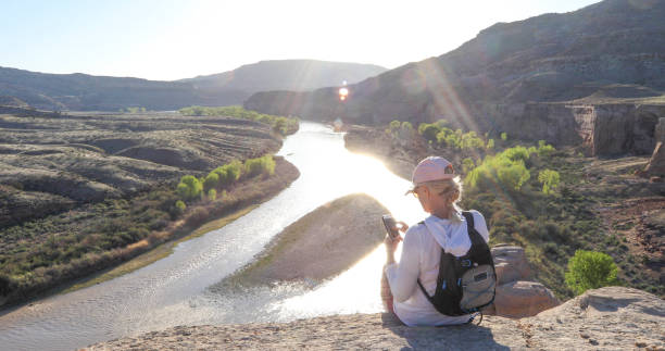 l'escursionista maturo si ferma sul bordo del canyon e usa il suo telefono cellulare - pink hat foto e immagini stock