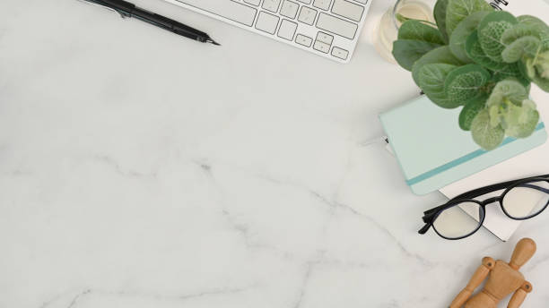 istock Top view of comfortable workspace with houseplant, glasses, notebook and copy space on marble table. 1318394063