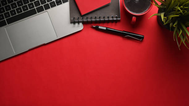 istock Stylish workspace with laptop, notebook, coffee cup and houseplant on red background. 1318394843