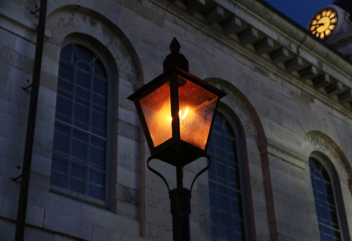 Real gaslit lamp in downtown Kingston, Ontario, Canada, photographed in front of Kingston's iconic city hall. Old fashioned gas lamp closeup stock photo.