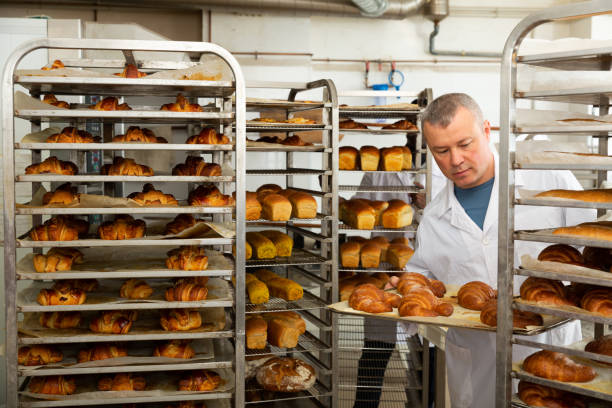 istock Baker putting tray with bakery goods on trolley 1318402119