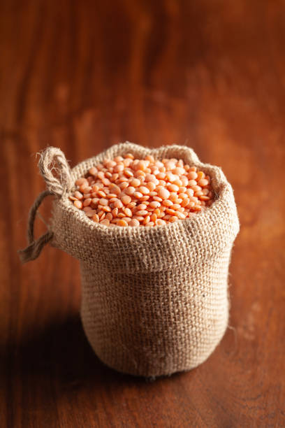 close-up of organic masoor dal (lens culinaris) or whole pink dal in  standing jute bag over wooden brown background. - lentil full frame macro close up imagens e fotografias de stock