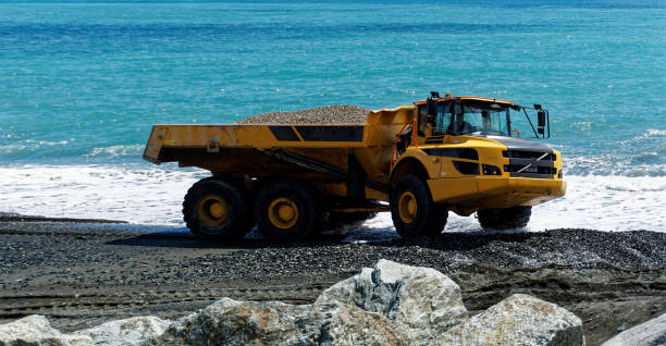 istock Industrial dumper trucks working on a construction in Genova city beach - Digging and moving sand with large dumper truck with sea in background 1318408016