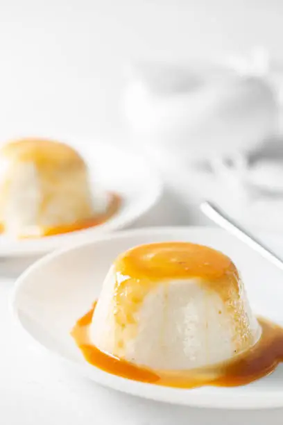 Photo of Panna cotta with pears - italian dessert of sweetened cream thickened with gelatin, with caramel sauce. High-key light. Vertical image.