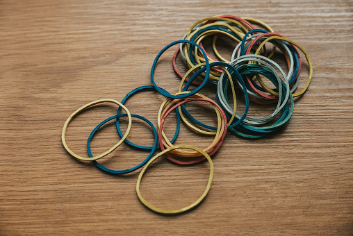 colourful multi coloured elastic rubber bands on wooden background.