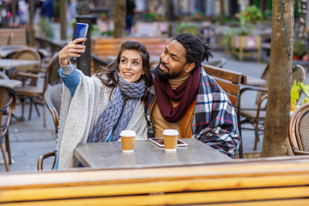 istock A Young Multi-Ethnic Couple is Spending a Wonderful Evening Together, Having a Lovely Communication and Sharing a Fresh Drink, and Taking Selfie Photos with Mobile Phone. 1318410981