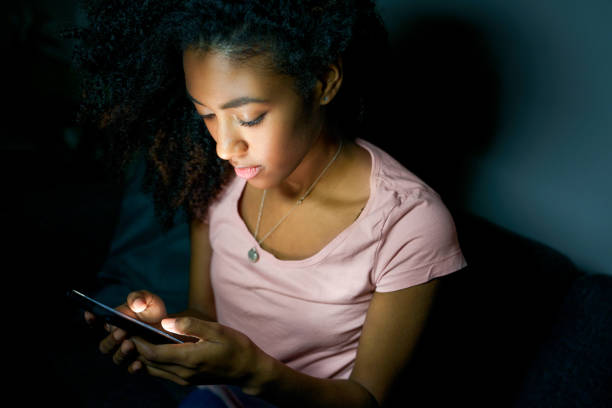 solo joven negra usando teléfono inteligente por la noche - addiction smart phone internet social networking fotografías e imágenes de stock