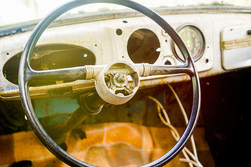 The steering wheel of an old rusty passenger car
