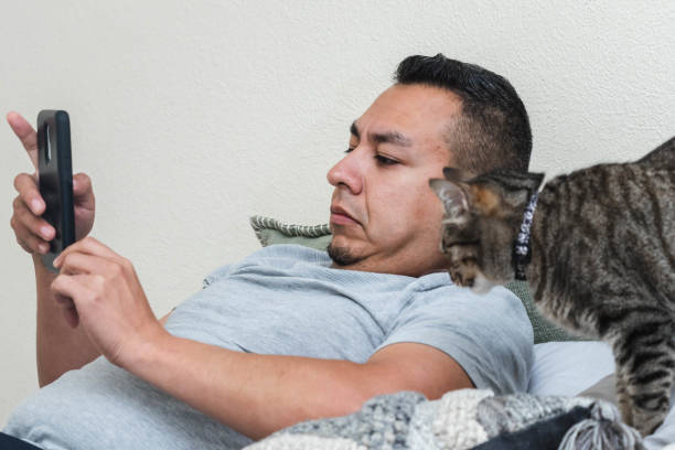istock Man & Cat Look At Smartphone Together 1318412853