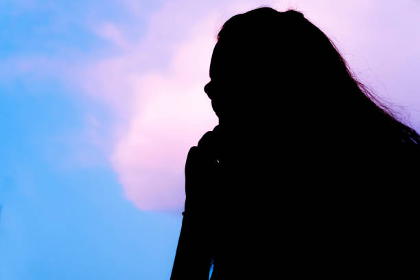 istock Silhouette image young woman talking on the phone against a blue cloudy sky. 1318414817