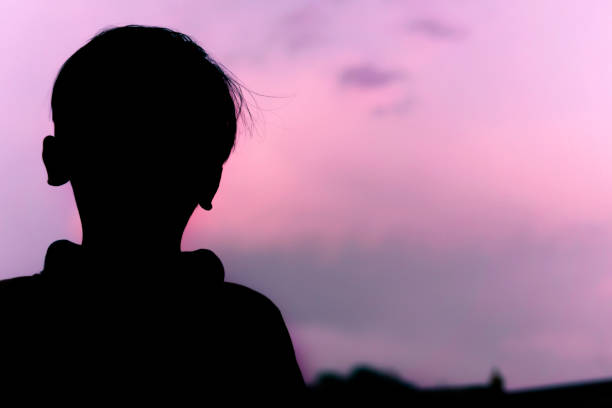 istock Silhouette image little boy standing against blue cloudy sky. 1318414855