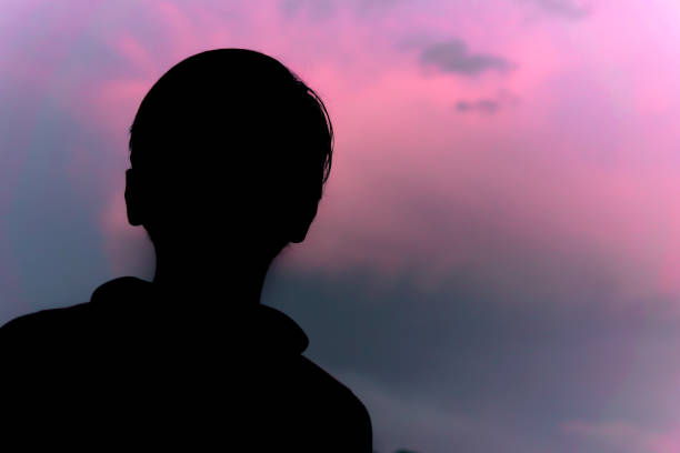 istock Silhouette image little boy standing against blue cloudy sky. 1318414894