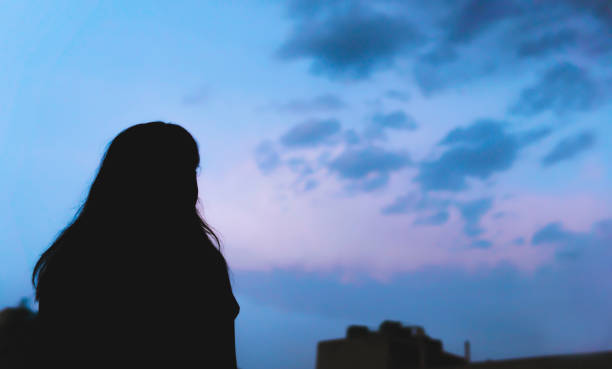 istock Silhouette image young woman contemplating against blue cloudy sky. 1318414973