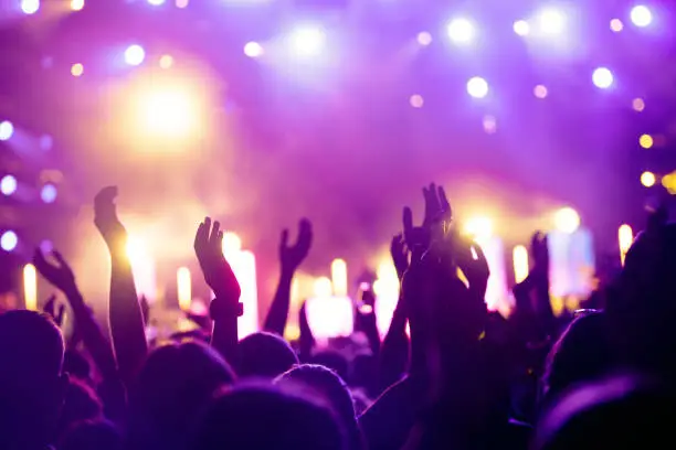 Photo of Cheering crowd with hands in air at music festival