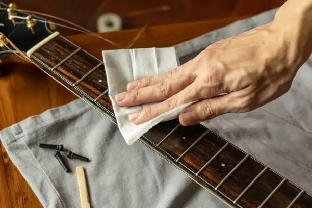 Photo of Cleaning guitar fretboard with wet wipes made for guitar
