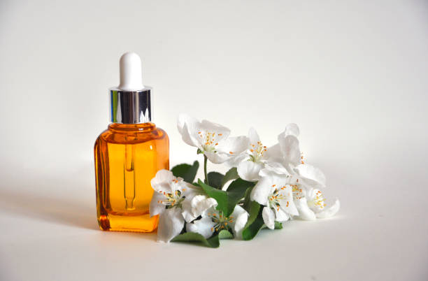 istock Yellow glass bottle with white flowers on a white background. Mockup 1318424540