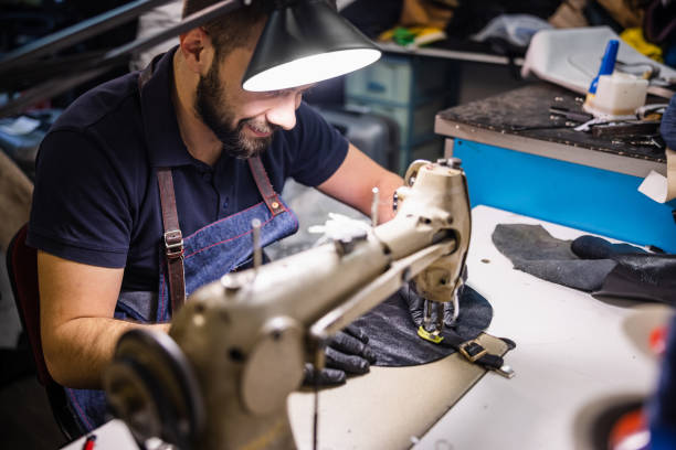istock Young man stitching a piece of black leather on special sewing machine 1318424936