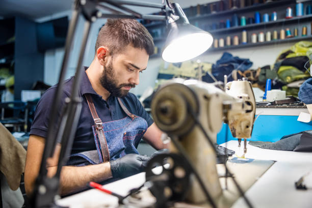 istock Young man working on piece of leather, sewing machine on workbench 1318424960