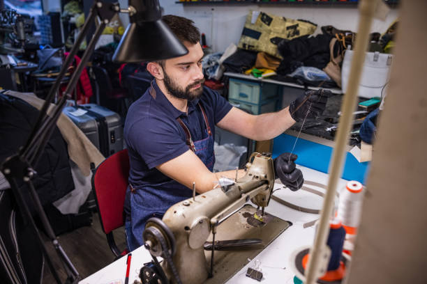 istock Young man in crafts repair shop holding thread for sewing machine 1318424961
