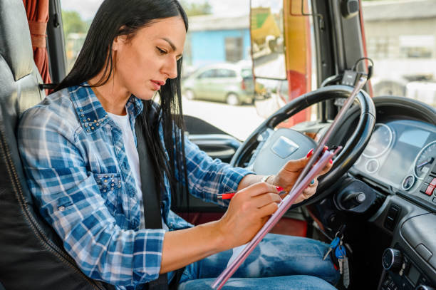 istock Female truck driver using a mobile app and writing on a clipboard 1318427813