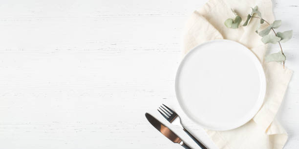 istock An empty plate and cutlery on a white table. 1318429828