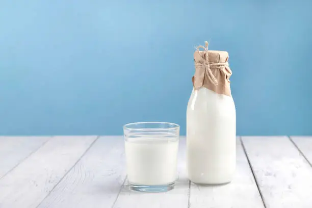 Photo of A glass with kefir, homemade yogurt or vegetable milk on a white table and next to a bottle with a drink. Space for text, horizontal photo