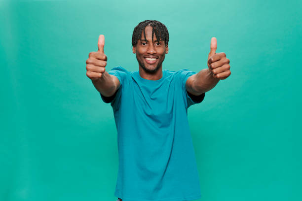 istock Young Black Wearing a blue t-shirt Over A Turquoise Background 1318430726