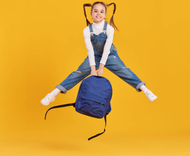 istock Cheerful schoolgirl with backpack having fin and jumping 1318431275