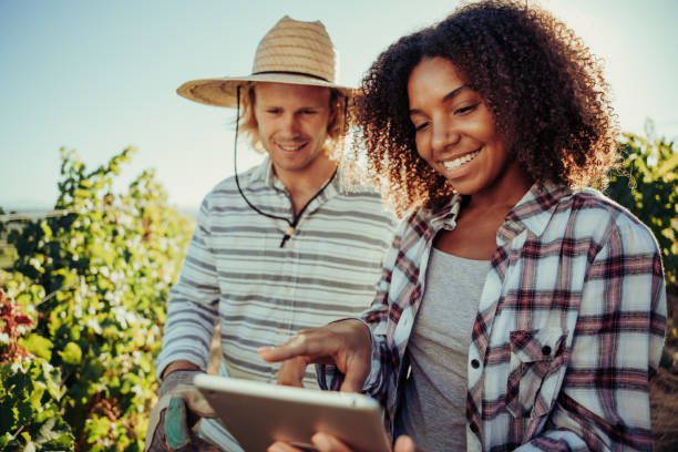 istock Diverse farmer couple working together on project standing in vineyards researching information on digital tablet 1318432436