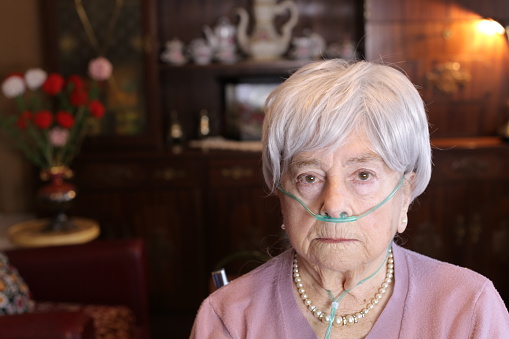 Senior woman using nasal breathing aid at home.