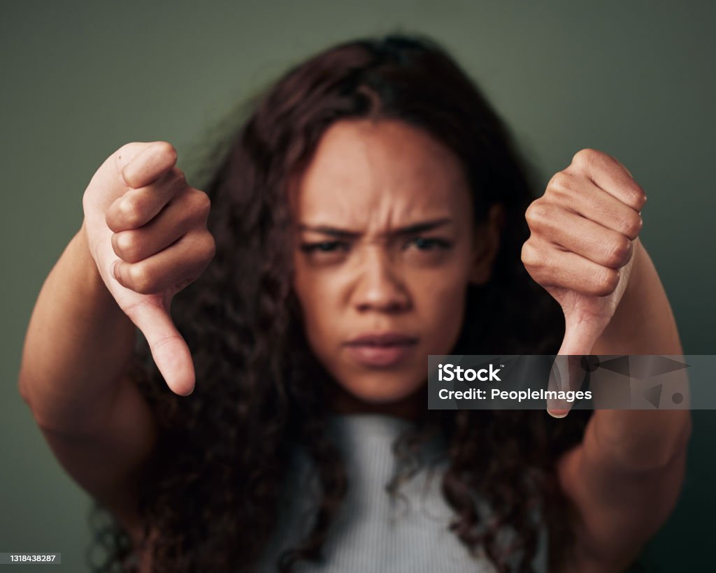 Studio shot of a young woman showing thus down against a green background That gets a downvote from me Thumbs Down Stock Photo
