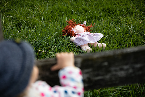 Adorable baby girl playing with a doll outdoors. Little child having fun. Kid playing  with a stuffed toy.