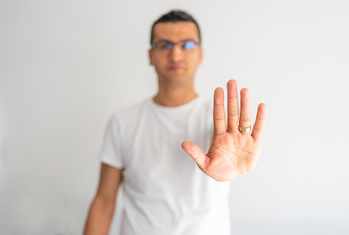 Young man making stop gesture with palm of his hand. Concept of stop. Hand showing stop sign