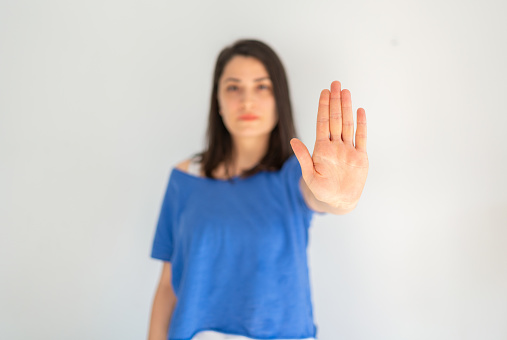 Young woman making stop gesture with palm of her hand. Concept of stop. Hand showing stop sign