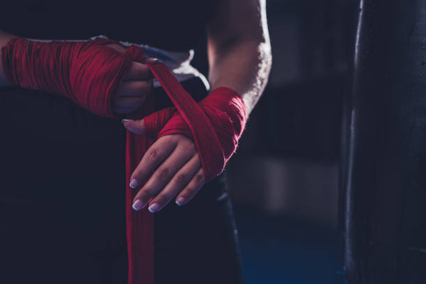 boxeur féminin méconnaissable appliquant le bandage adhésif à portée de main avant l’entraînement de boxe - boxing womens photos et images de collection