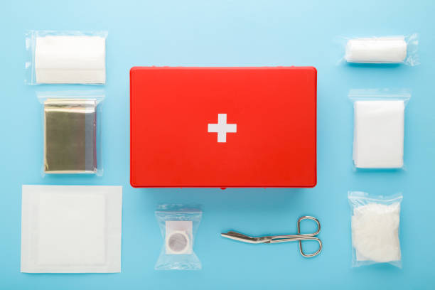 diferentes accesorios médicos en paquetes alrededor de la caja roja del botiquín de primeros auxilios sobre el fondo azul claro de la mesa. color pastel. closeup. vista arriba hacia abajo. - bandage sheers fotografías e imágenes de stock