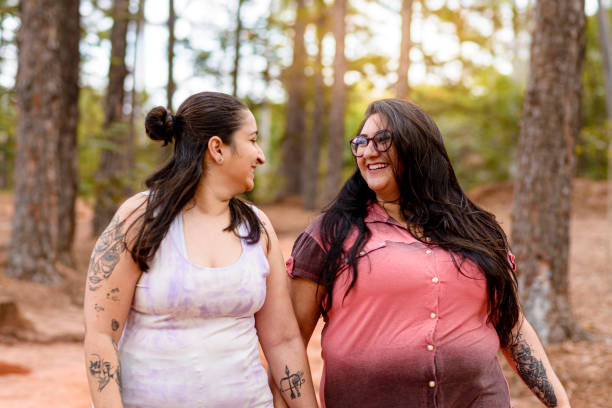 Couple of women in love smiling during walk in wooded forest stock photo