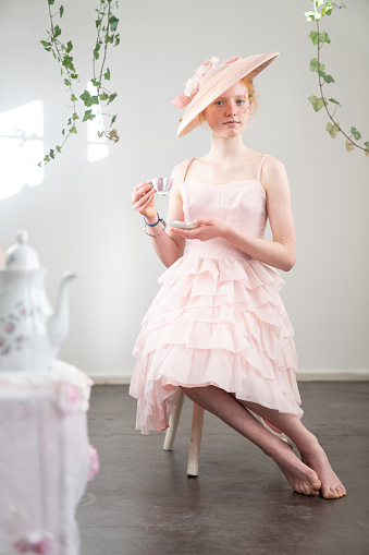 Vintage Girl in pink hat and dress drinking a cup of tea