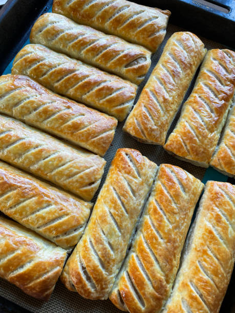 istock Full frame image of rows, golden brown, fresh crunchy sausage rolls, elevated view 1318447793