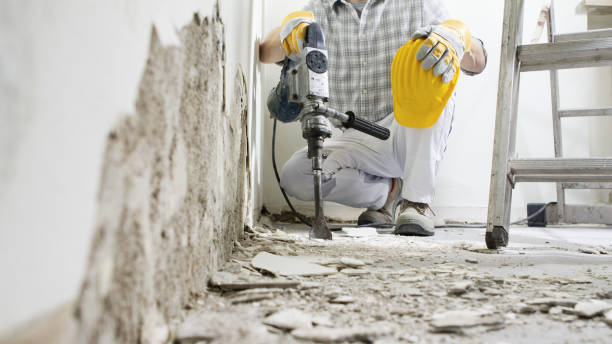 istock House renovation concept. Construction worker with protective gloves and yellow helmet at work breaks the wall with the jackhammer, plaster rubble and ladder on the white background. 1318448069