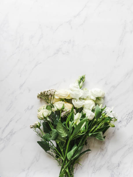 istock Bouquet of various white flowers border on marble background. Ranunculus, eustoma, roses, alstroemeria in bouquet. 1318449338